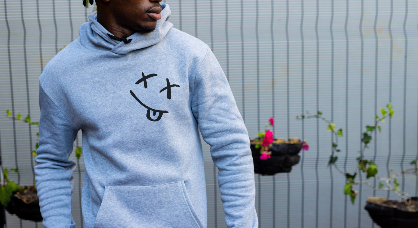 Person wearing a light grey hoodie with a graphic design, standing outdoors.